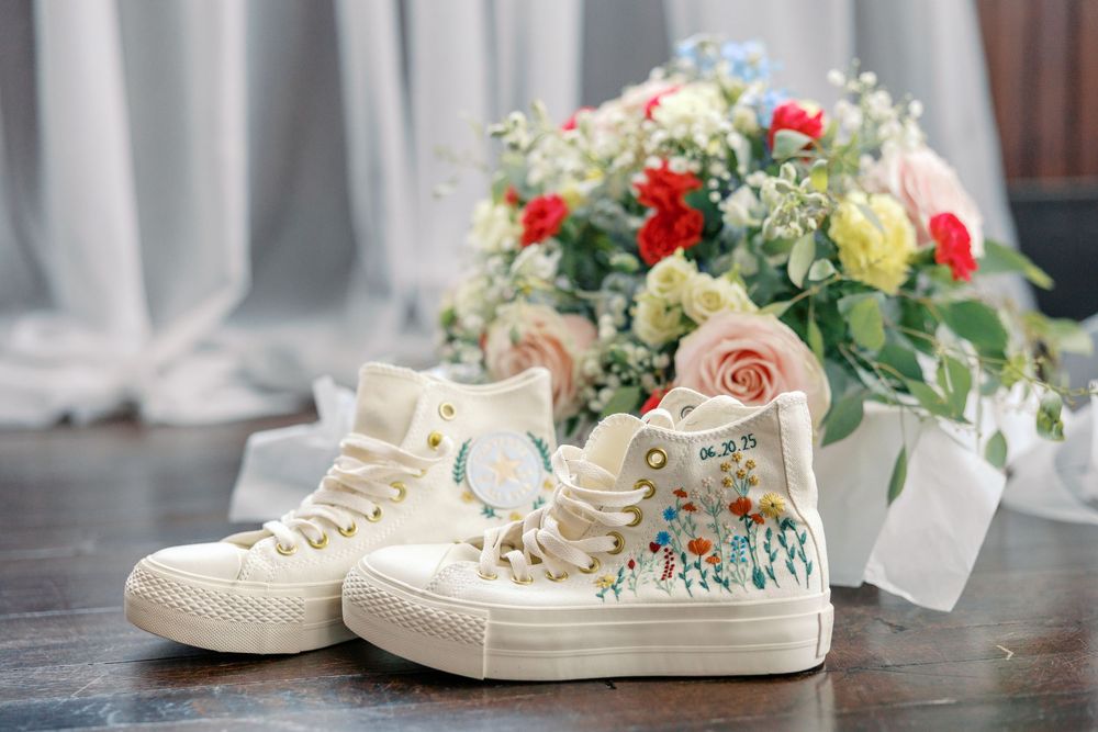 White wedding sneakers decorated with pearls and flowers are arranged in a romantic display for a bride.