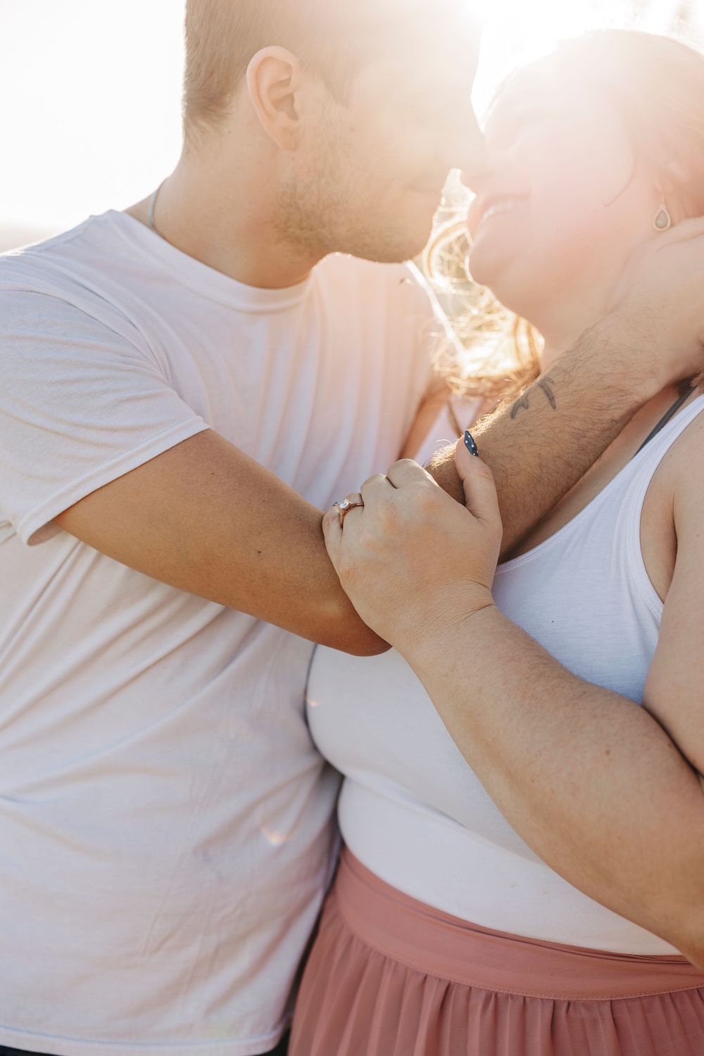 Romantic couple sharing an intimate moment together with sunlight and lens flare creating a warm backlit glow.