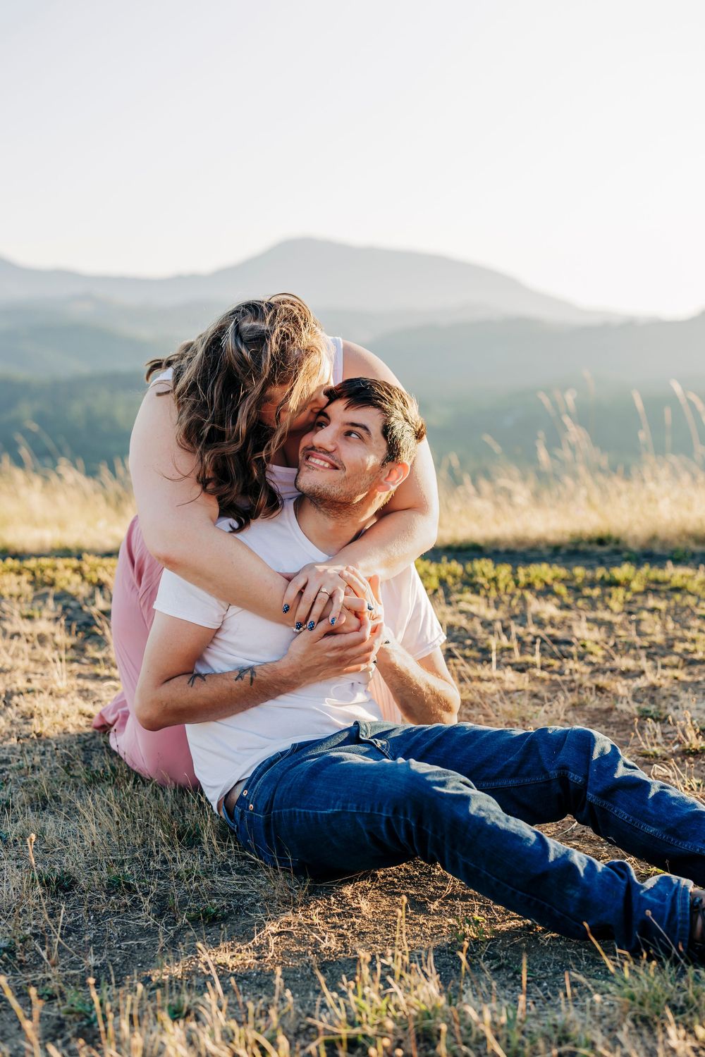 A tender embrace captured in golden light on a mountainside meadow at sunset.