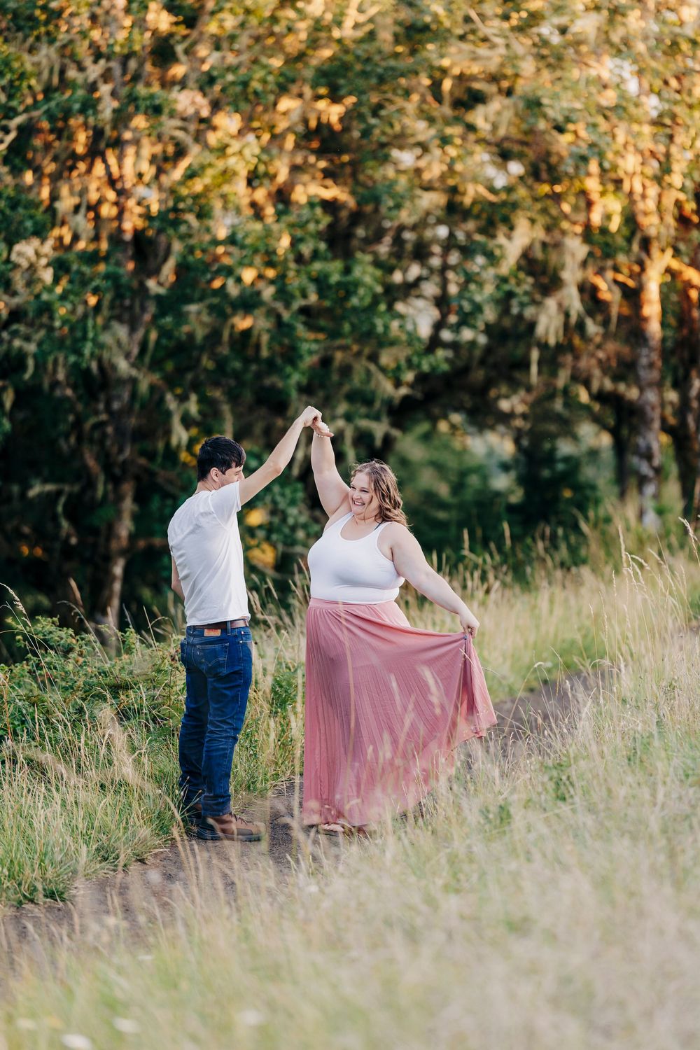 Dancing couple twirls in a meadow at sunset, with the person in a flowing pink skirt.