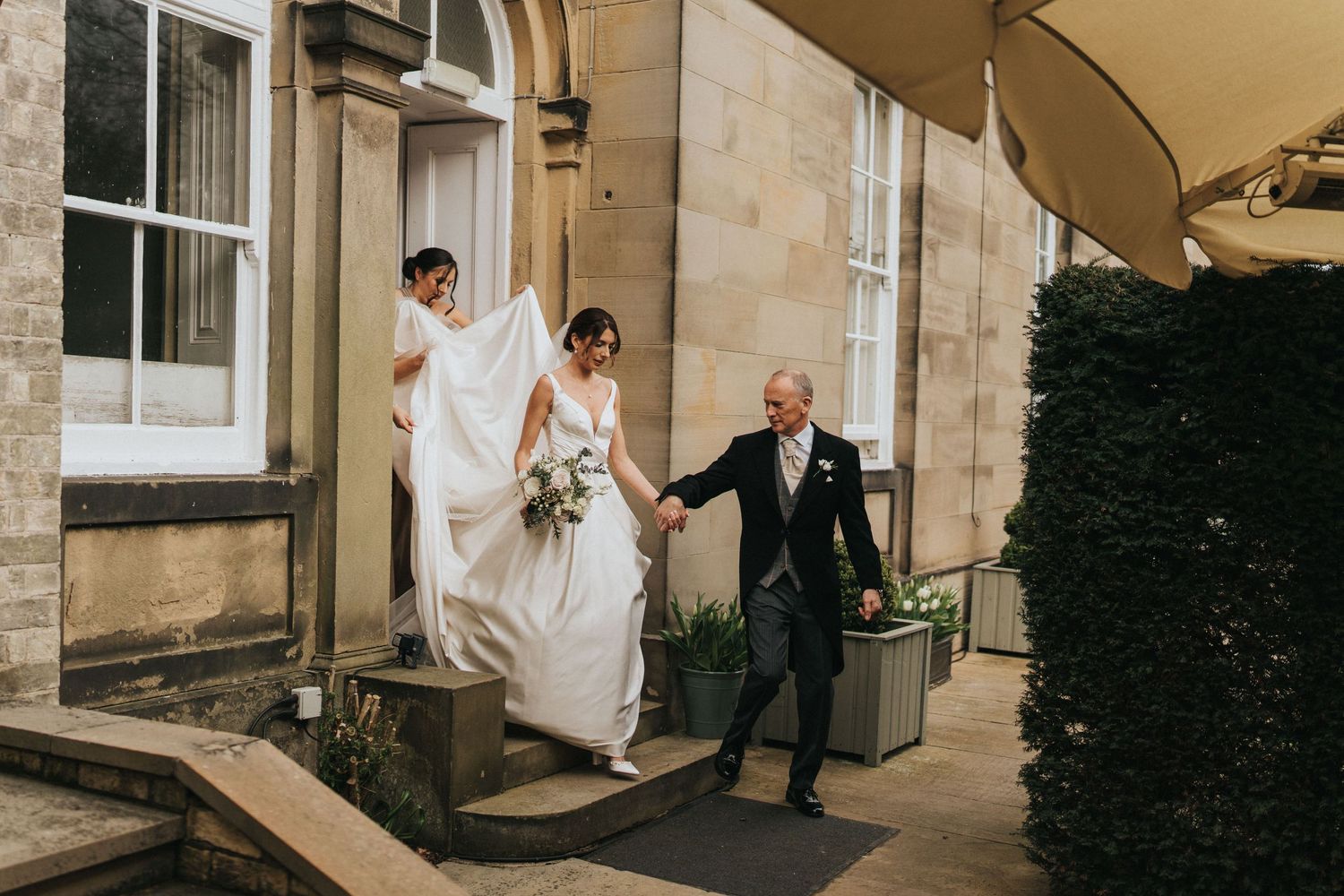 A wedding party assists bride along the entrance steps of Saltmarshe Hall - taken by Grimsby photographer.