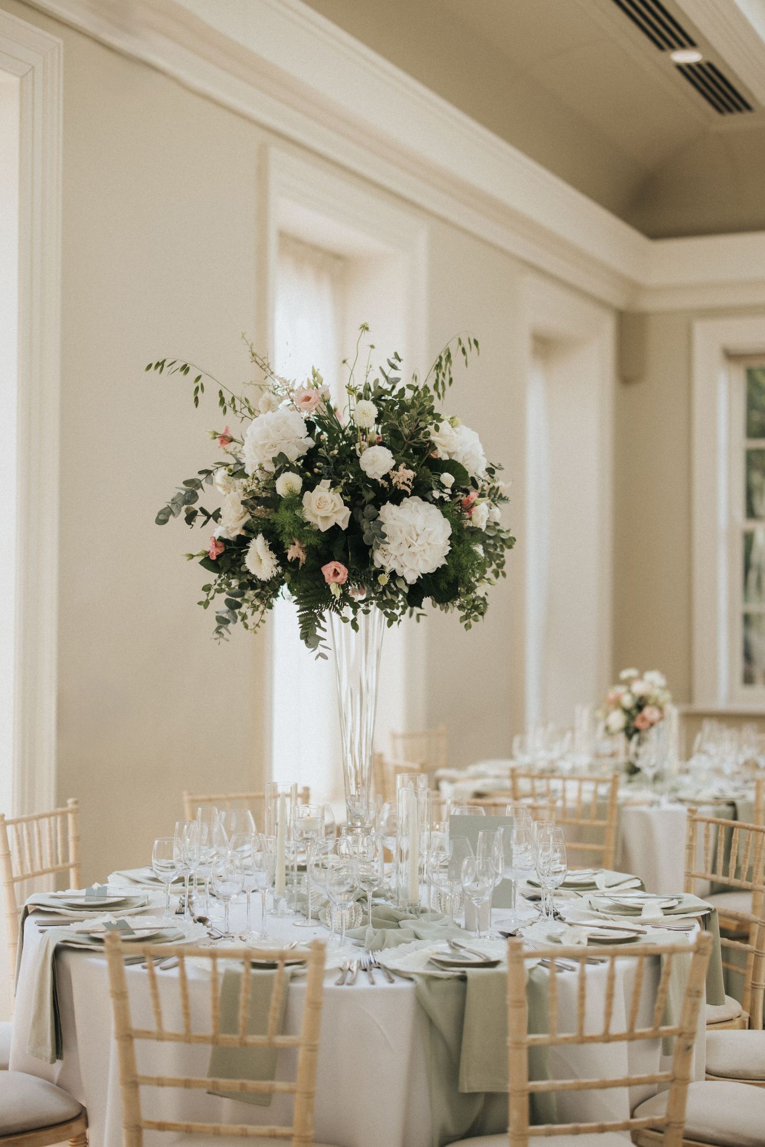Elegant wedding reception tables decorated with white floral centrepieces and chiavari chairs at Saltmarshe Hall.