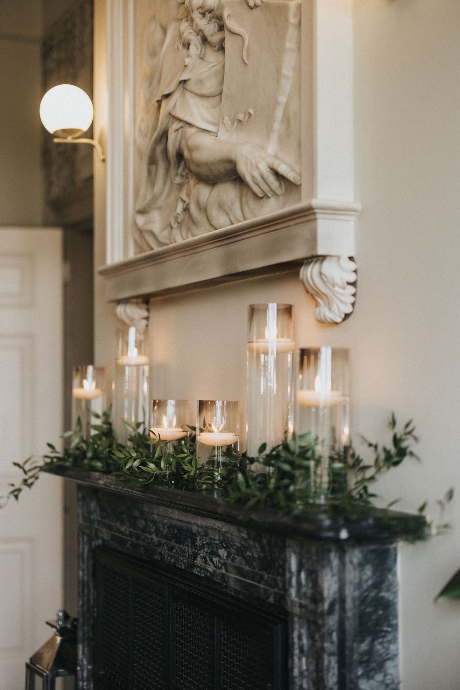 Glass candles with greenery decorate an elegant marble fireplace mantel at Saltmarshe Hall - taken by Grimsby photographer.