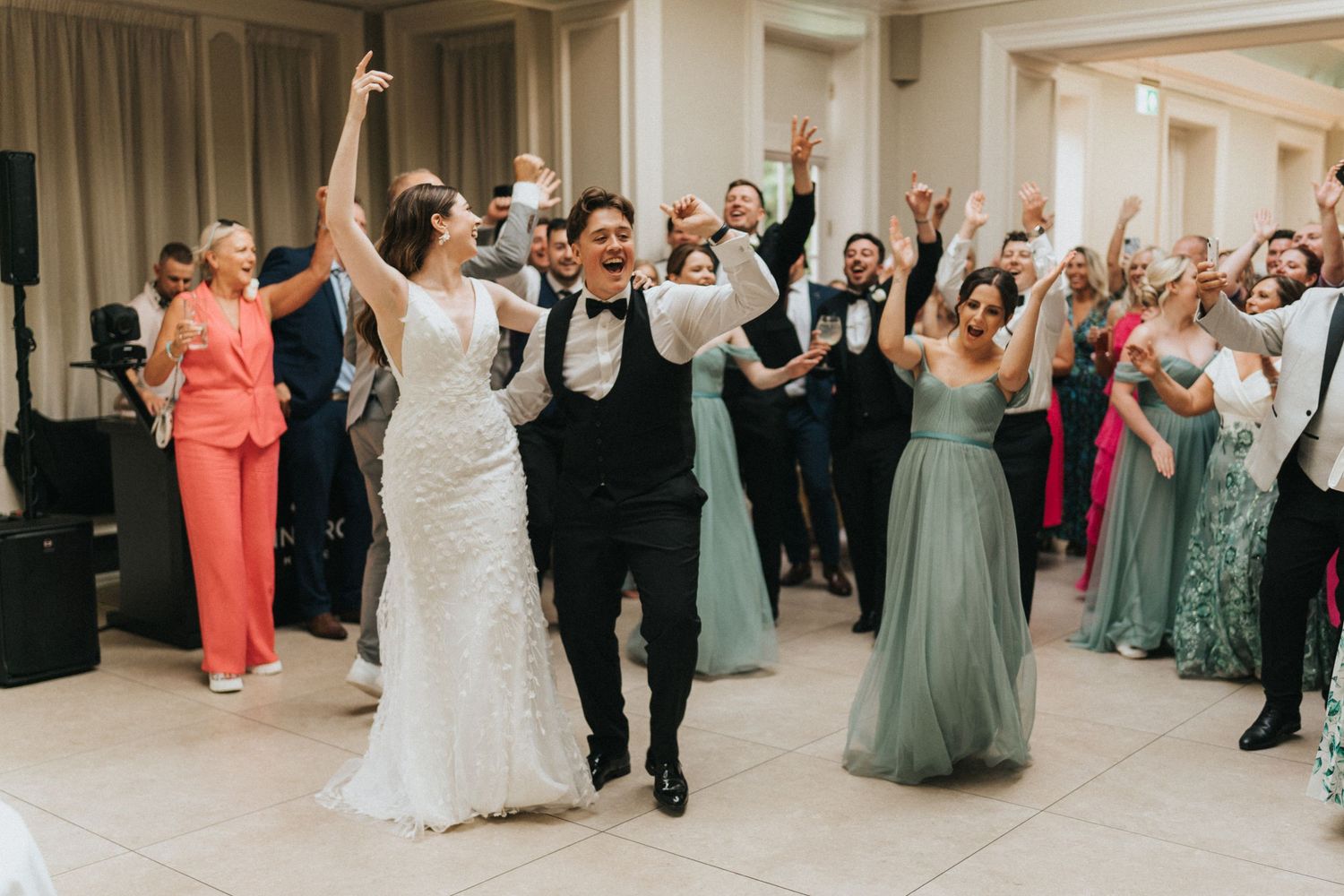 Wedding reception celebration with guests dancing and cheering in a ballroom with elegant decor at Saltmarshe Hall.