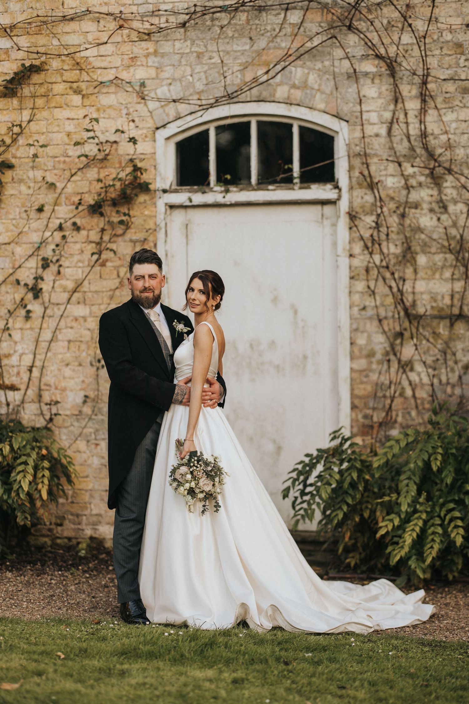 A romantic wedding couple poses against an ivy-covered stone wall in intimate portrait shots at Saltmarshe Hall - taken by Grimsby phot