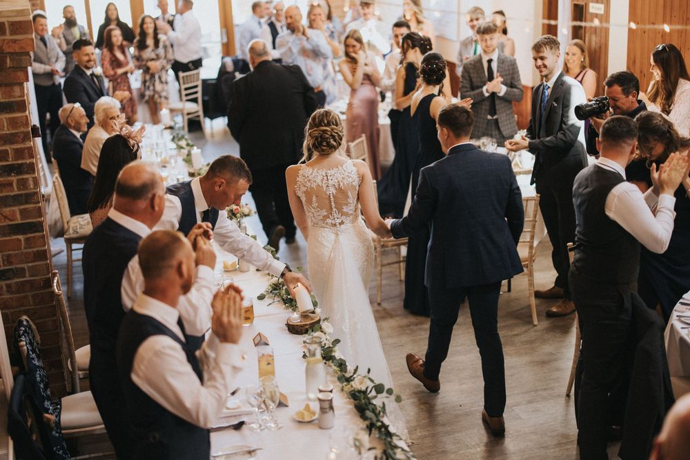 Wedding reception guests mingle in an elegant brick-walled venue at Hall Farm - image captured by Grimsby photographers.