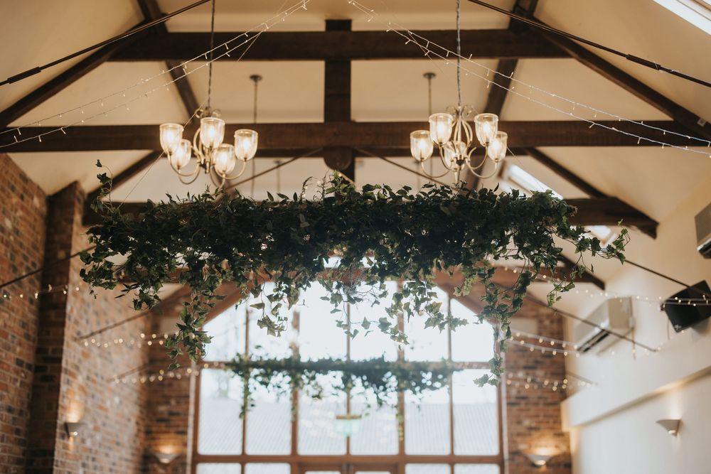 Elegant rustic venue interior with exposed beams, chandeliers and greenery garland at Hall Farm - image captured by Grimsby photographers.