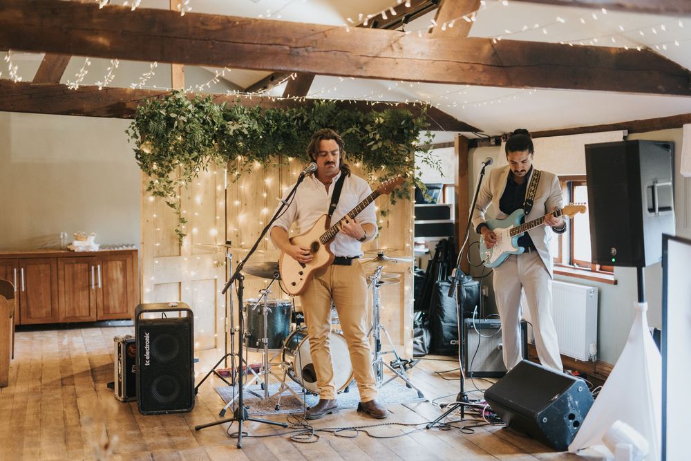 A band performs with string lights and wooden beams overhead at Hall Farm - image captured by Grimsby photographers.