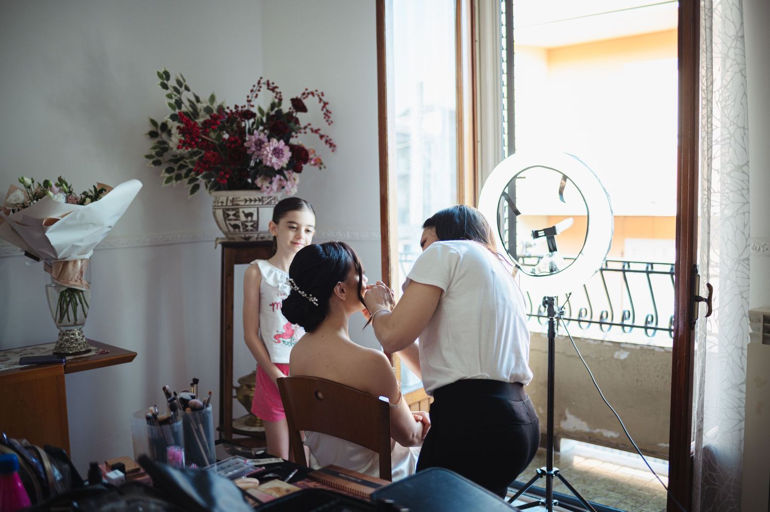A bright interior room with windows and floral arrangements visible.