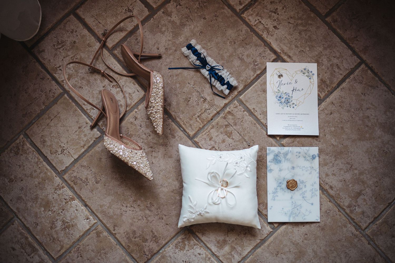 Elegant wax sealed wedding invitations with blue floral designs displayed on a rustic wooden table.