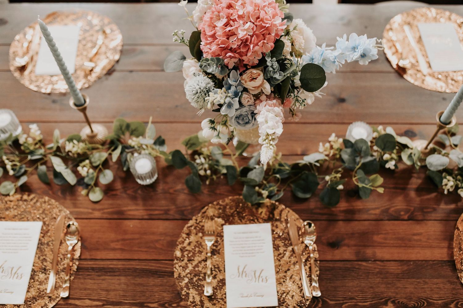Overhead table layout featuring sage green accents, wooden chargers, and vintage glassware