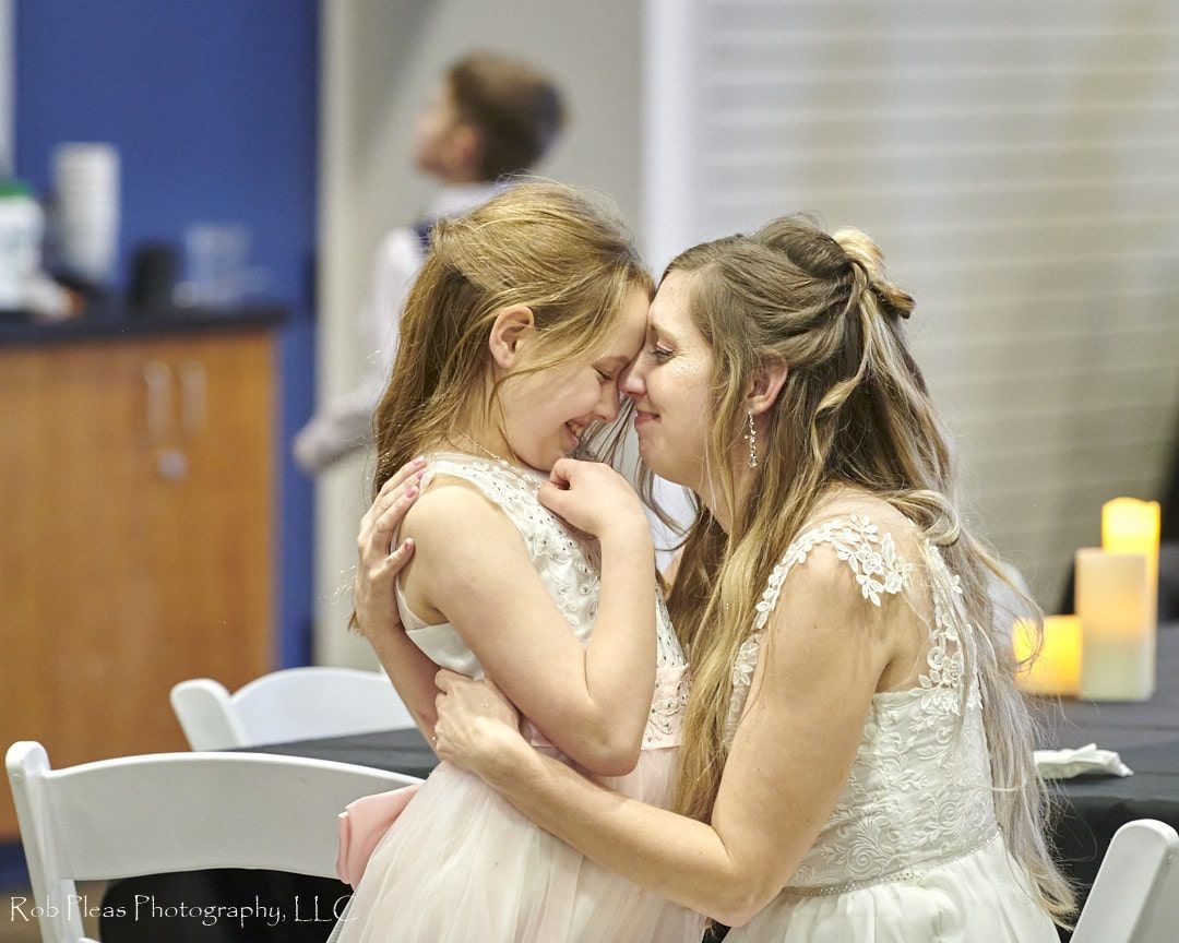 bride in playful moment, hugging daughter after ceremony, before reception.