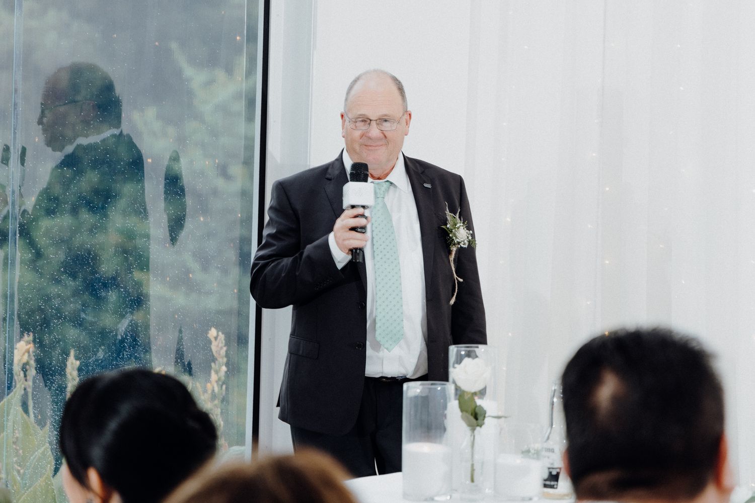 A person in a dark suit delivers a speech captured by Apertured Media Auckland Wedding Photographer.