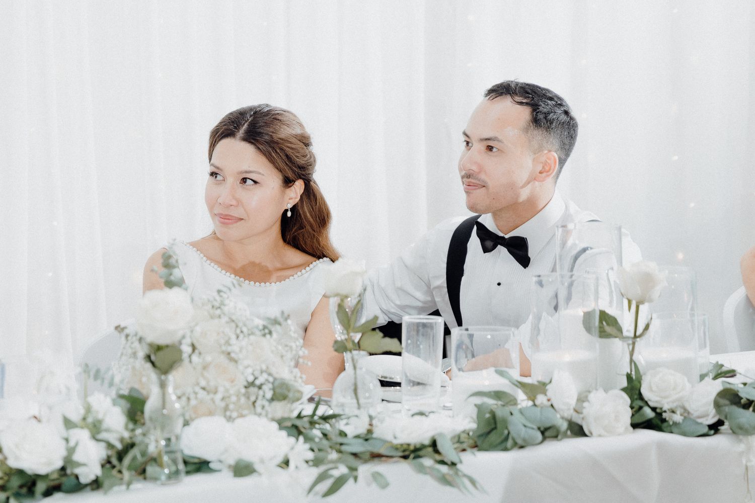 Wedding couple sits at elegant reception table listening to speeches captured by Apertured Media Auckland Wedding Photographer.