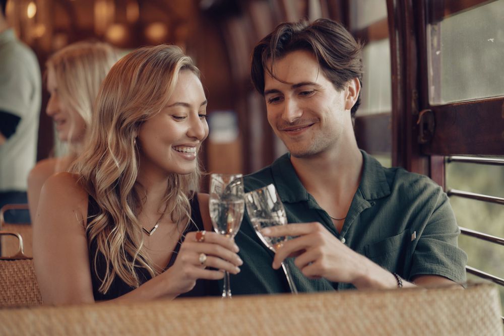 A couple shares a romantic moment while toasting with wine glasses in a cozy space photographed by Evan Will