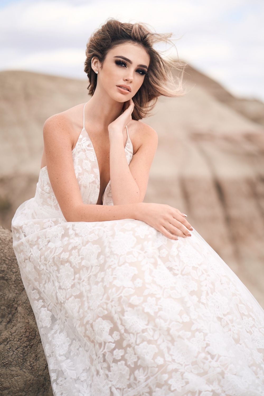 A beautiful lace wedding dress with plunging neckline and delicate floral details photographed against desert rock formations.