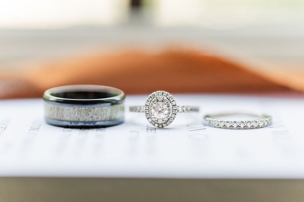 Three wedding rings including a sparkling diamond engagement ring and bands displayed on white surface.