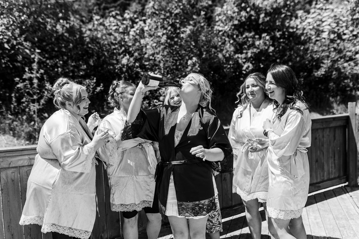 A sequence of black and white photos showing a group of people in white clothing laughing and embracing in an outdoor setting.