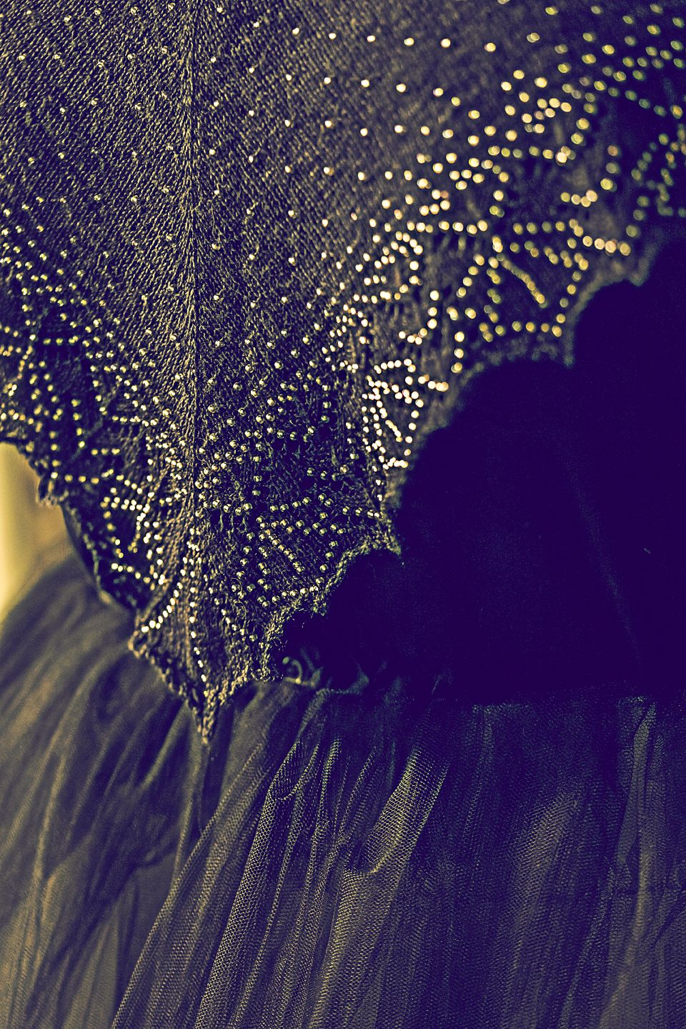 Close-up view of delicate lace fabric with intricate patterns illuminated against a dark background.