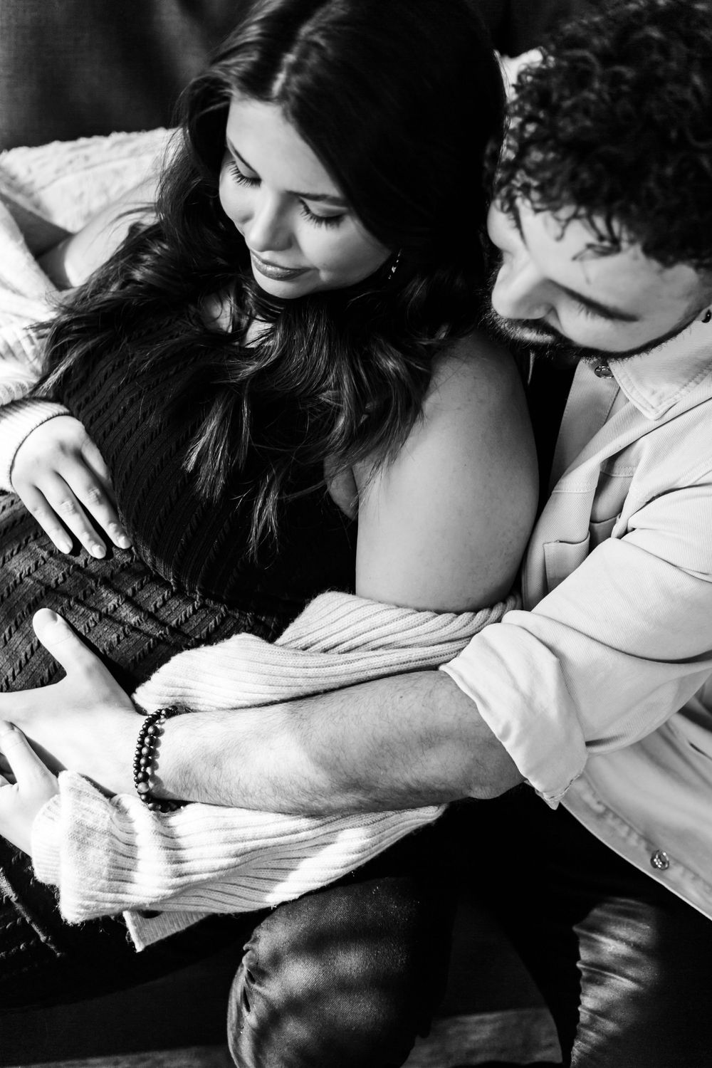 Black and white intimate photographs showing a couple in close embrace on a sofa.