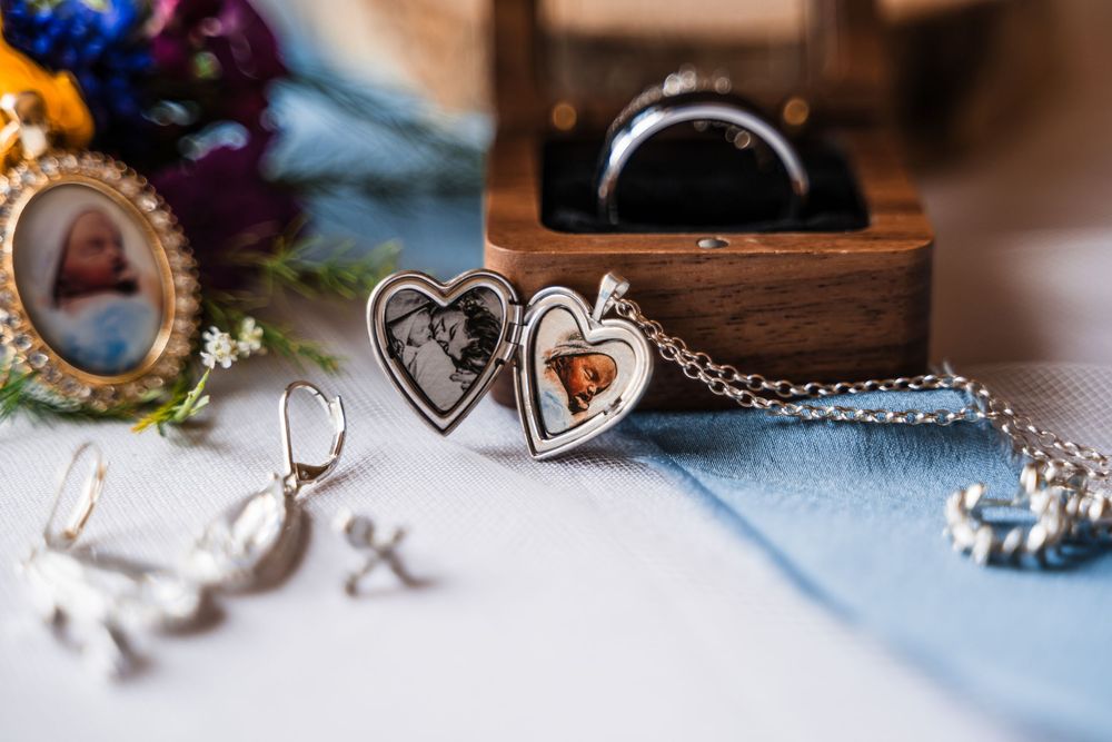 Heart-shaped locket necklaces and jewelry arranged on blue fabric.