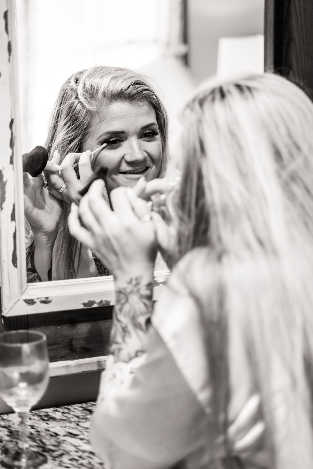 Getting ready scene reflected in mirror showing application of makeup.