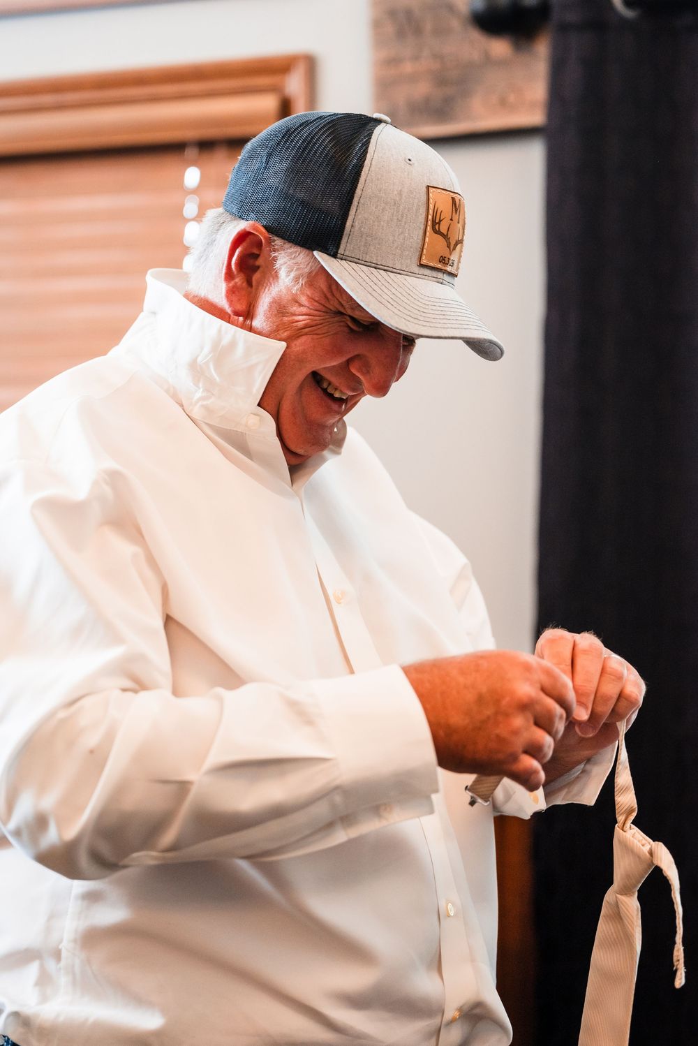 Person in white dress shirt and baseball cap getting ready before an event.