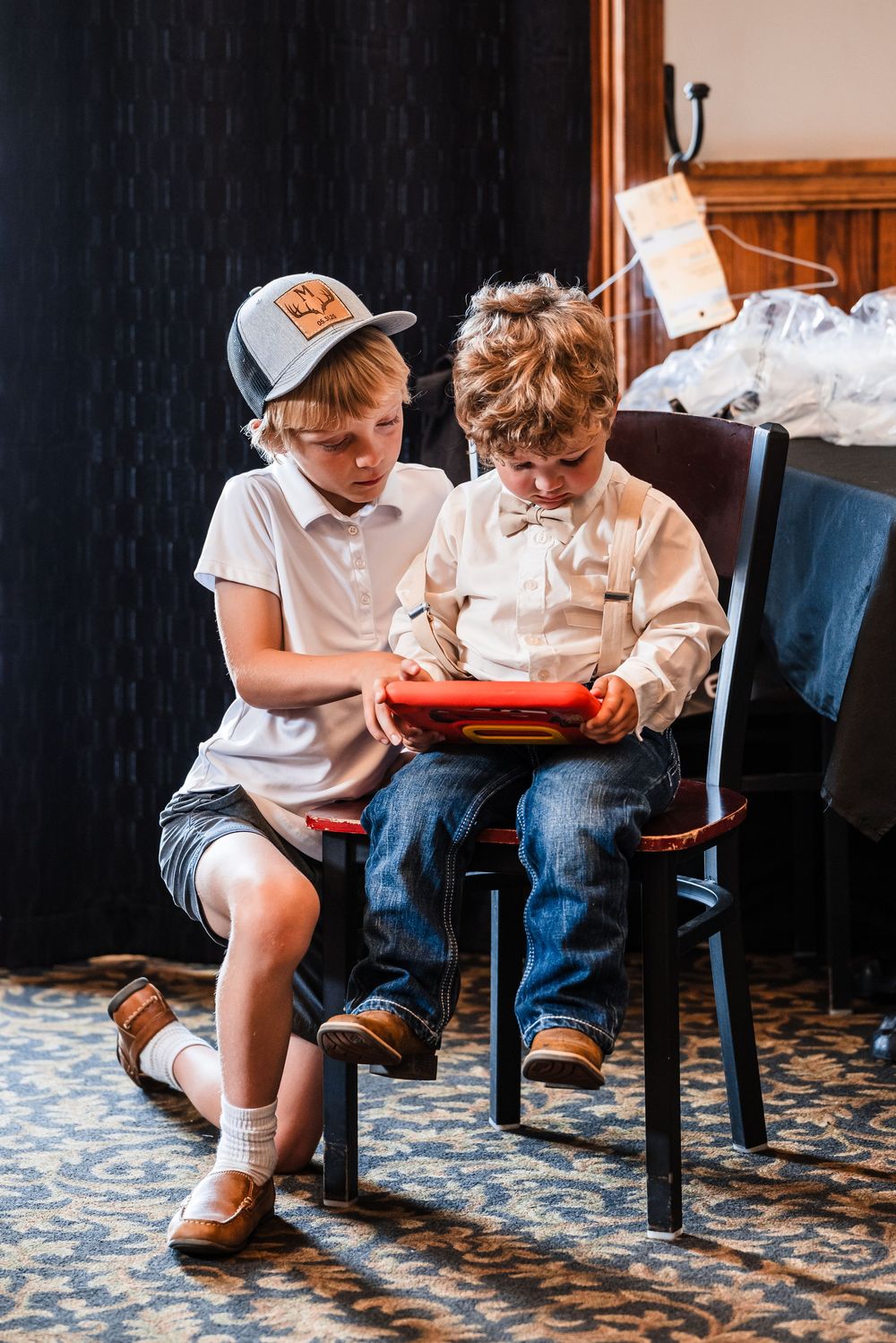 Two young guests in white shirts and jeans sitting together looking at something.