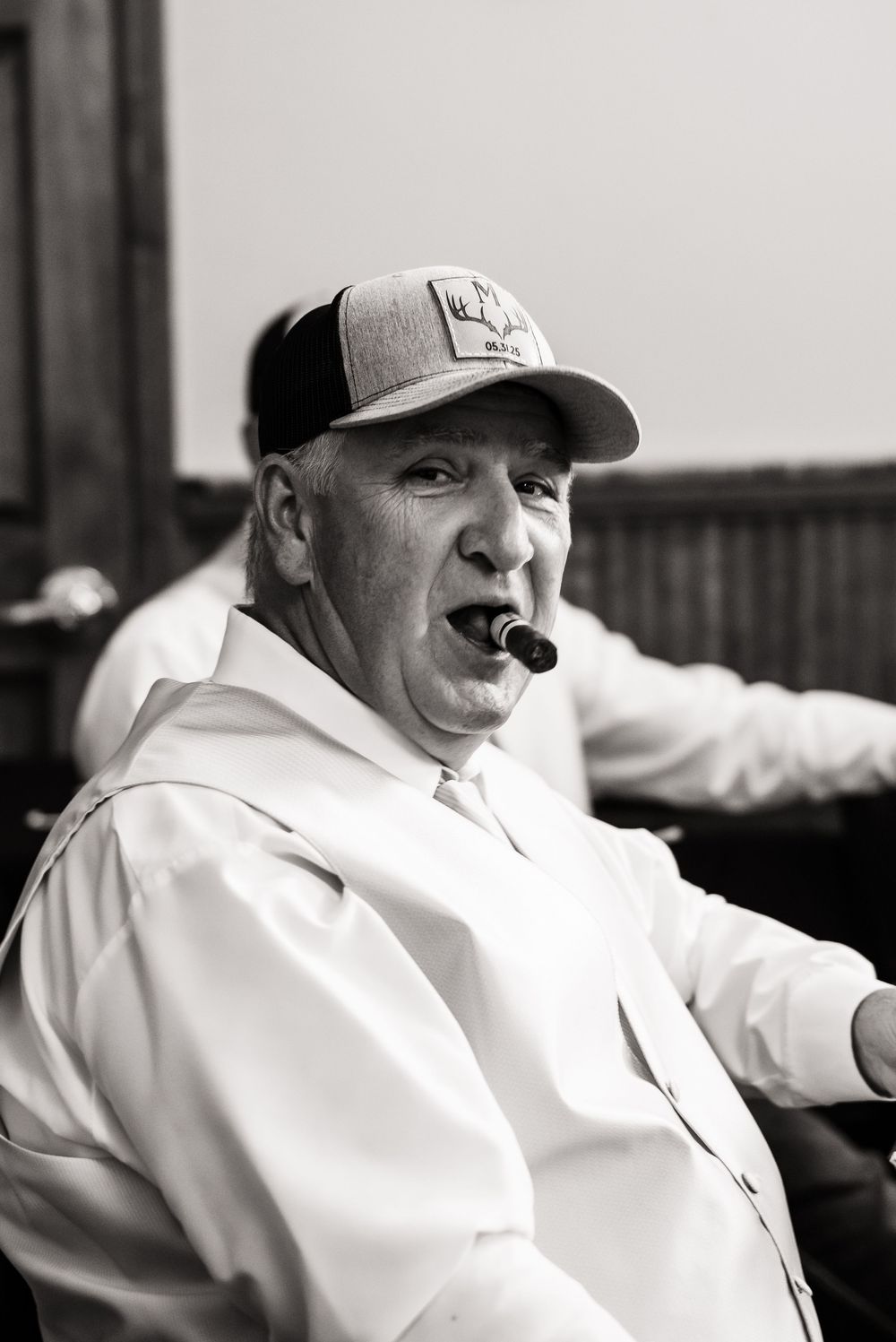 Black and white portrait showing joyful expression in casual baseball cap.