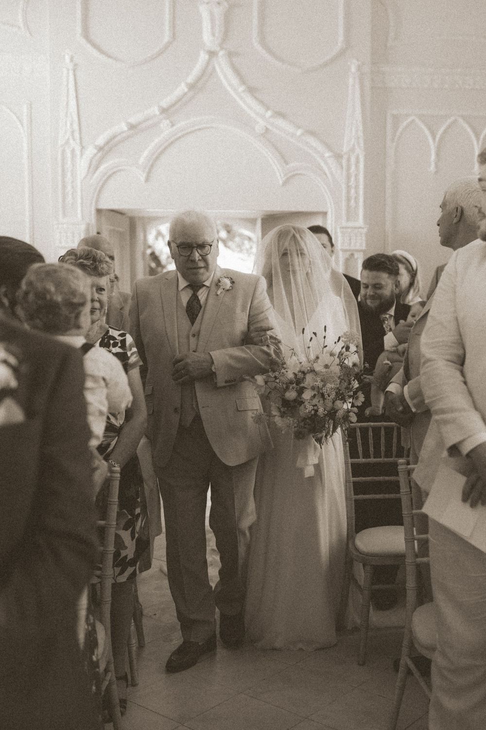A vintage sepia wedding photograph showing people gathered in a church aisle with Gothic architectural details.