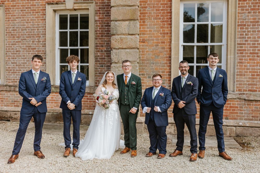 Bridal party sitting on brick wall showing off colorful dress socks and shoes at formal wedding.