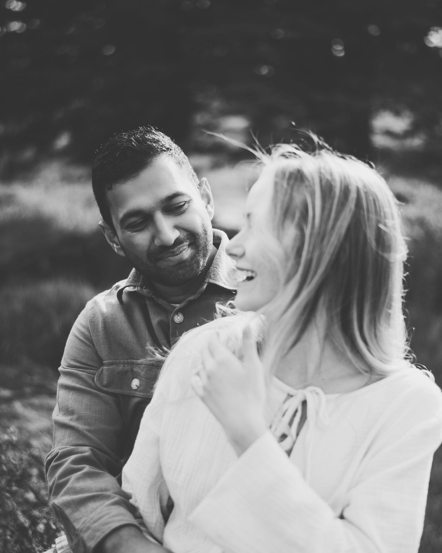 A close-up photo shows a happy couple looking affectionate, with a woman's hand displaying an engagement ring.