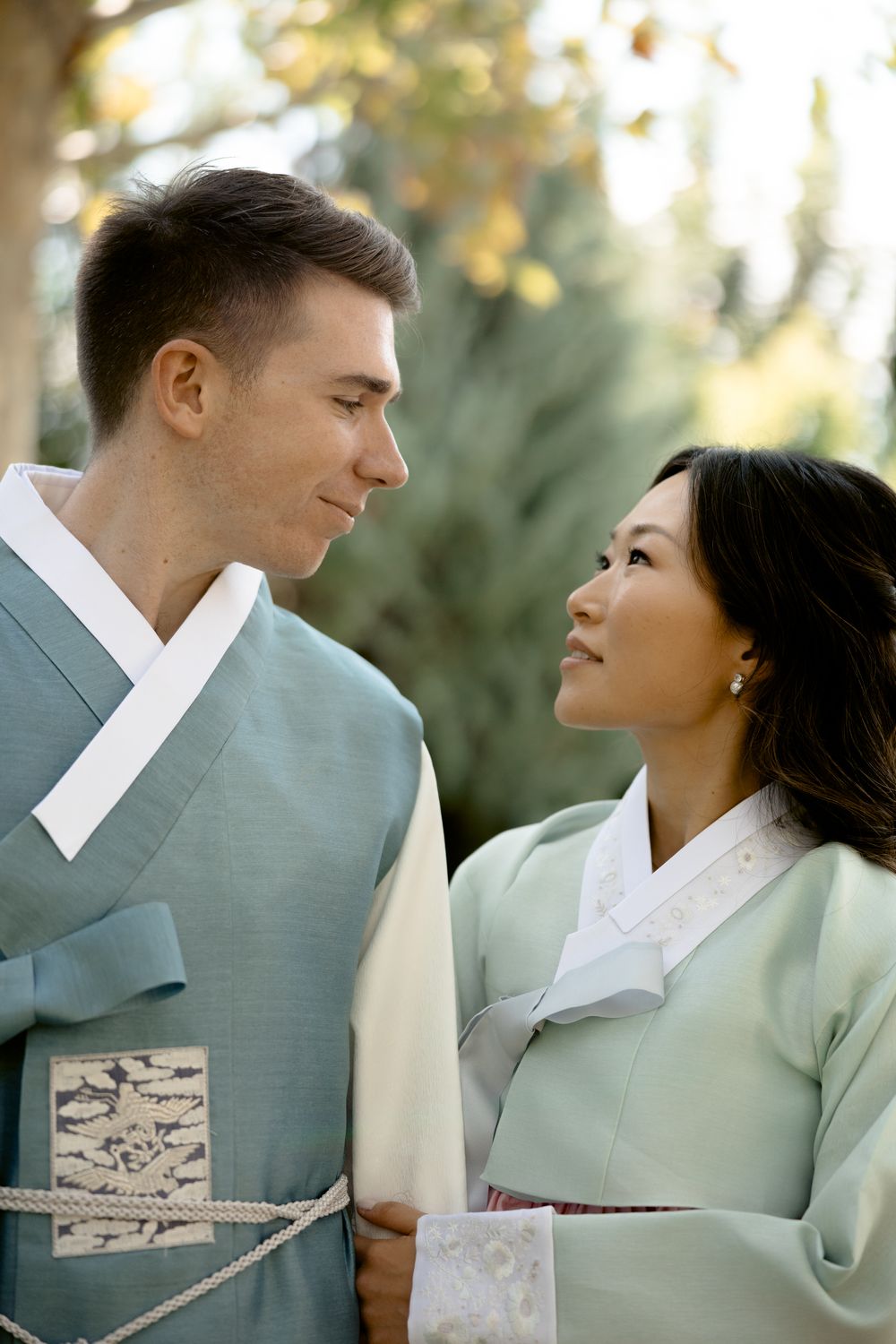 Couple in traditional Korean hanbok share an intimate moment in the garden. Athens wedding photographer