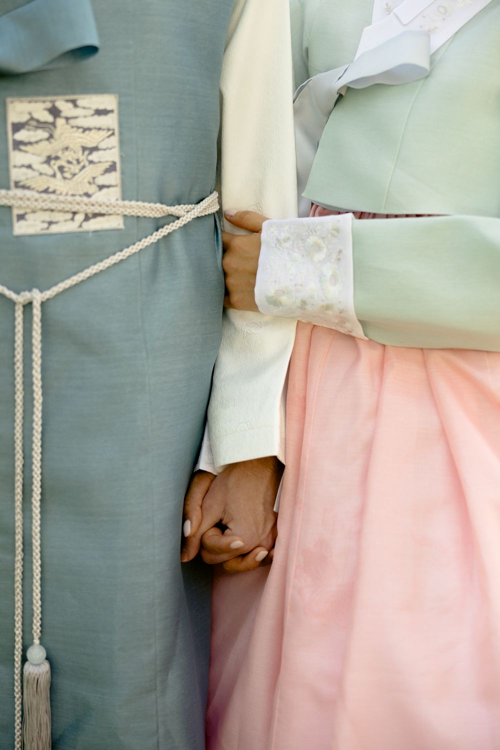 Close-up detail of traditional Korean hanbok outfits in mint green and pink. Athens wedding photographer