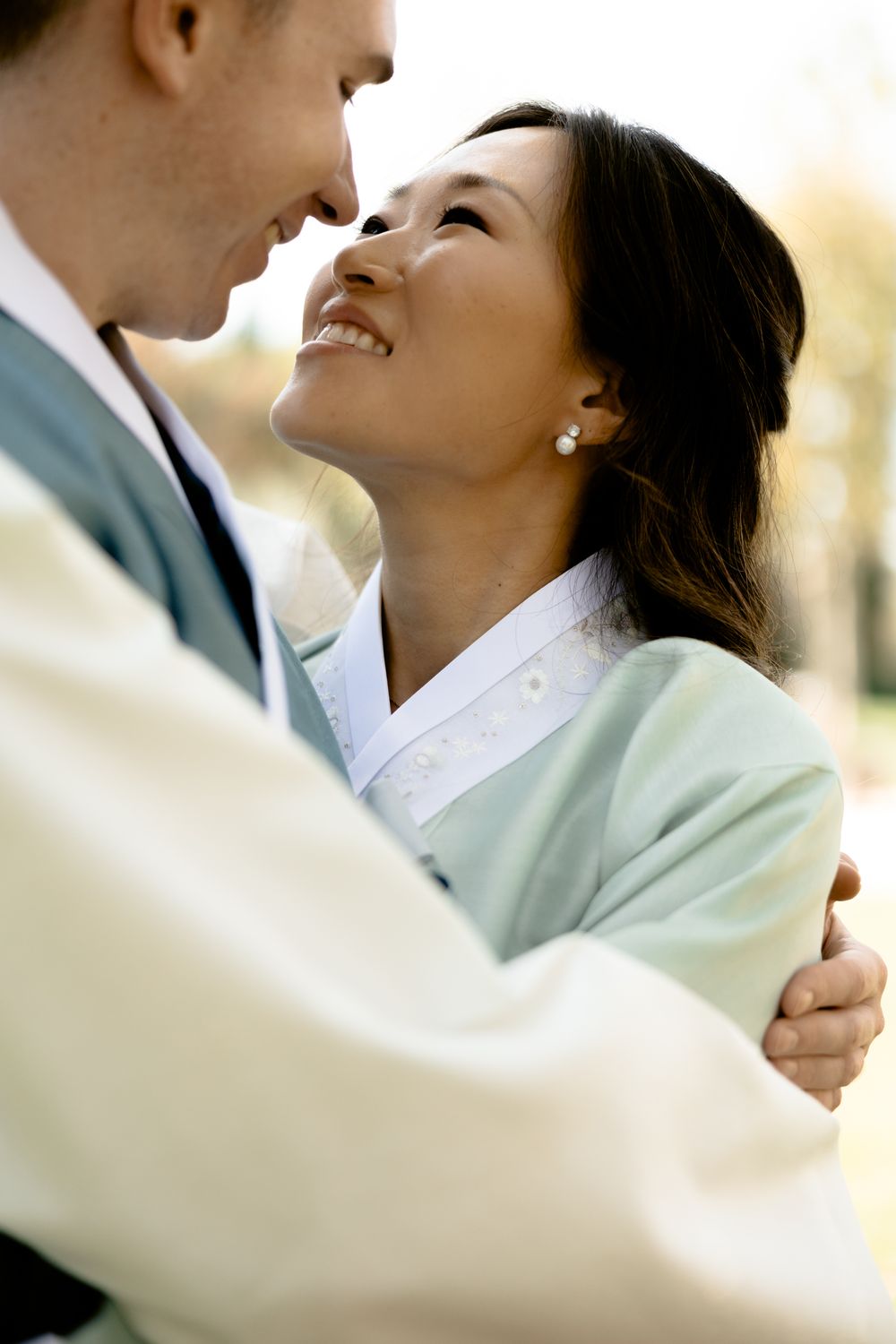 Intimate close-up of a couple in traditional Korean dress sharing a tender moment. Athens wedding photographer