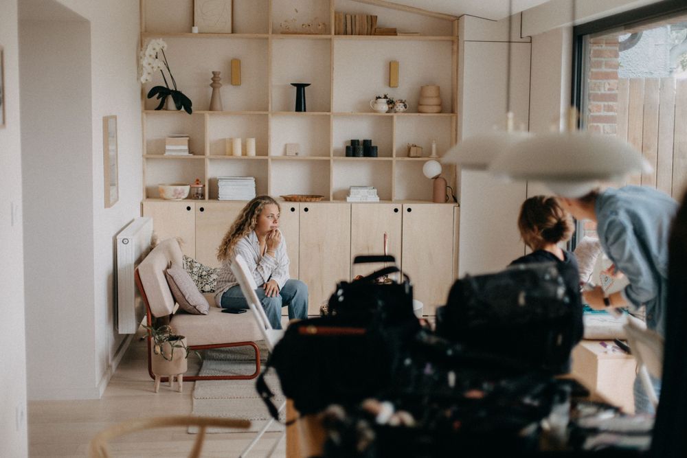 Behind-the-scenes photo shoot setup in bright interior with built-in shelving.