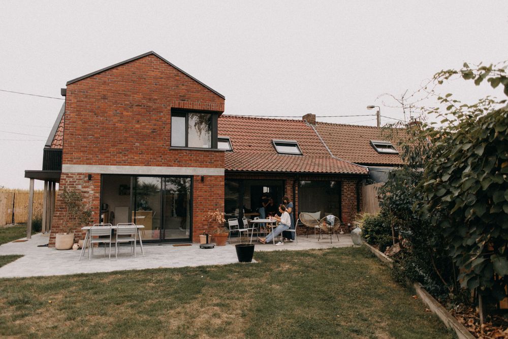 Modern brick house exterior with patio furniture and landscaped yard.