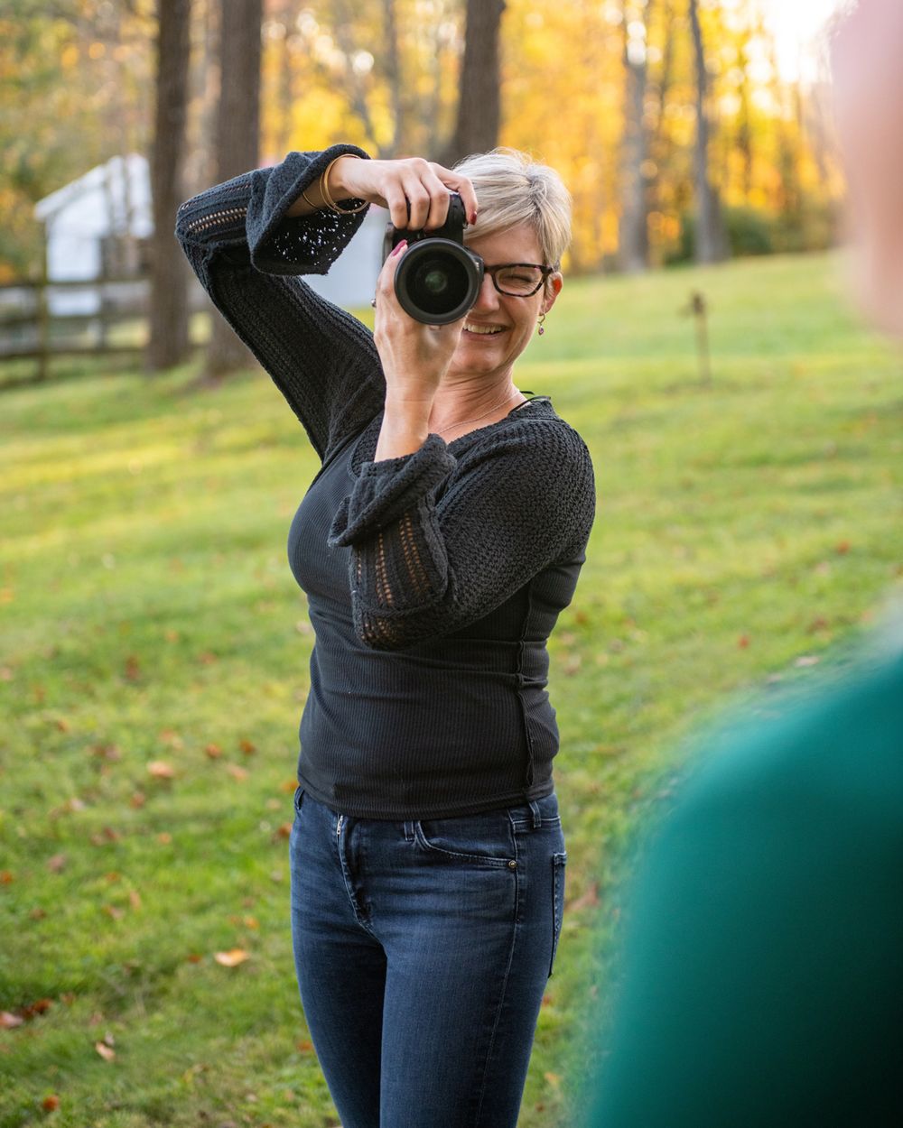 Photographer in black sweater taking pictures with professional camera in fall setting.
