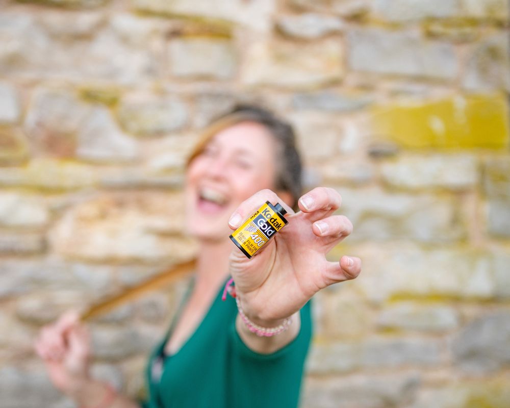 Hand holding small yellow tin can against stone wall background.