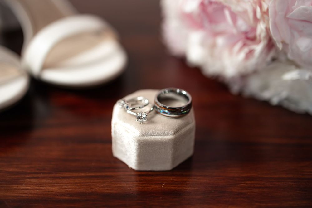 Diamond wedding rings in hexagonal box with soft focus floral background.