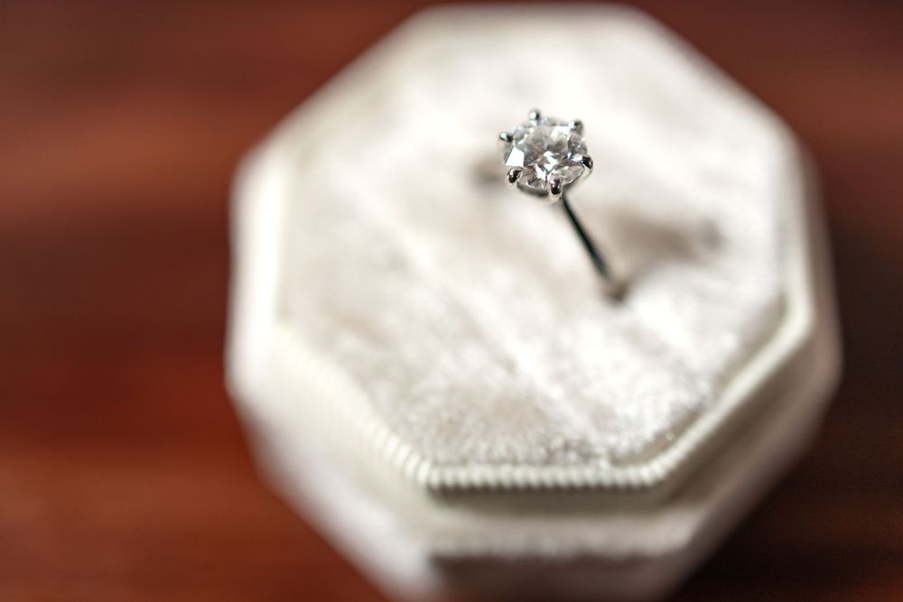Diamond solitaire engagement ring in white hexagonal box with soft focus effect.