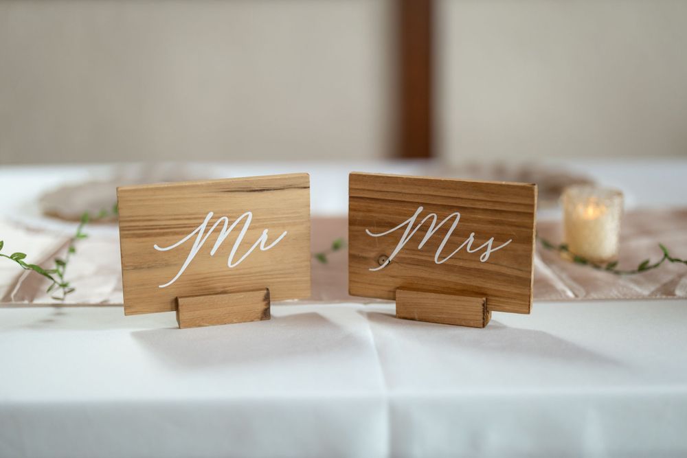 Wooden Mr and Mrs signs displayed on white tablecloth at wedding reception.