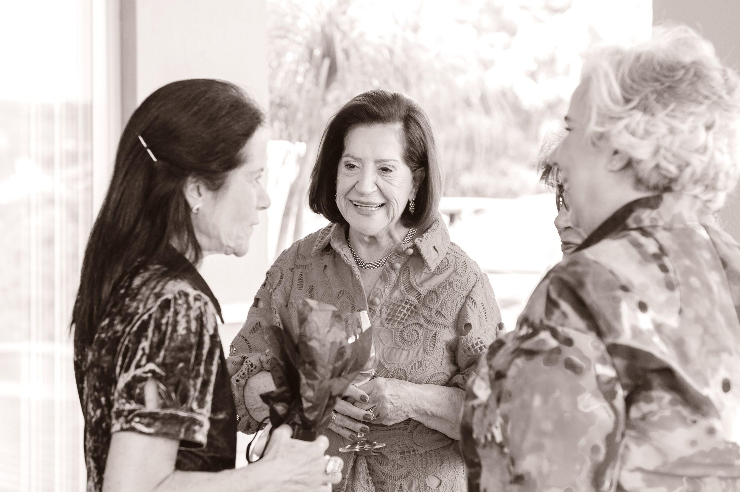 Three women engaged in lively conversation together while smiling and laughing in a casual setting.