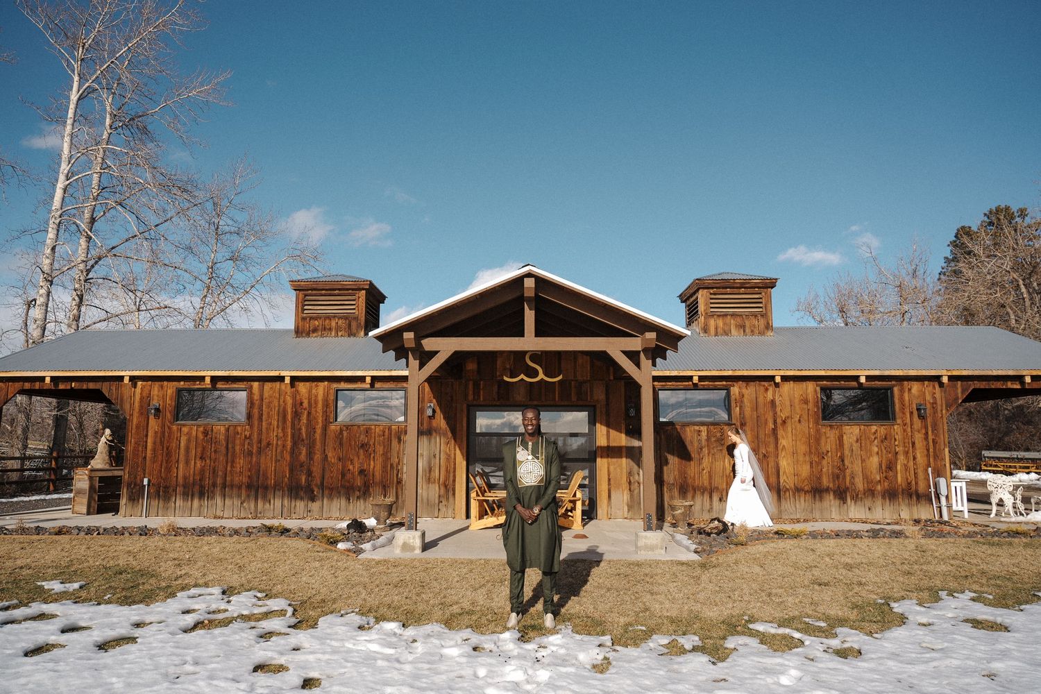 Rustic wooden barn venue with covered entrance on a snowy winter day during a wedding ceremony.
