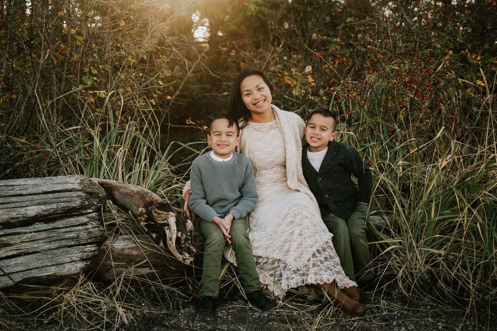 Beautiful soulfull portrait photography of mom and sons sitting on Madrona Point beach's rocky shore on Vancouver Island during golden hour