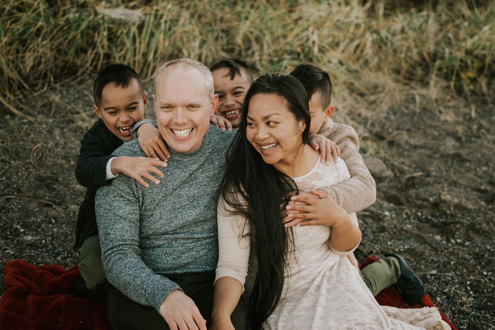 Beautiful soulfull portrait photography of family sitting on Madrona Point beach's rocky shore on Vancouver Island during golden hour