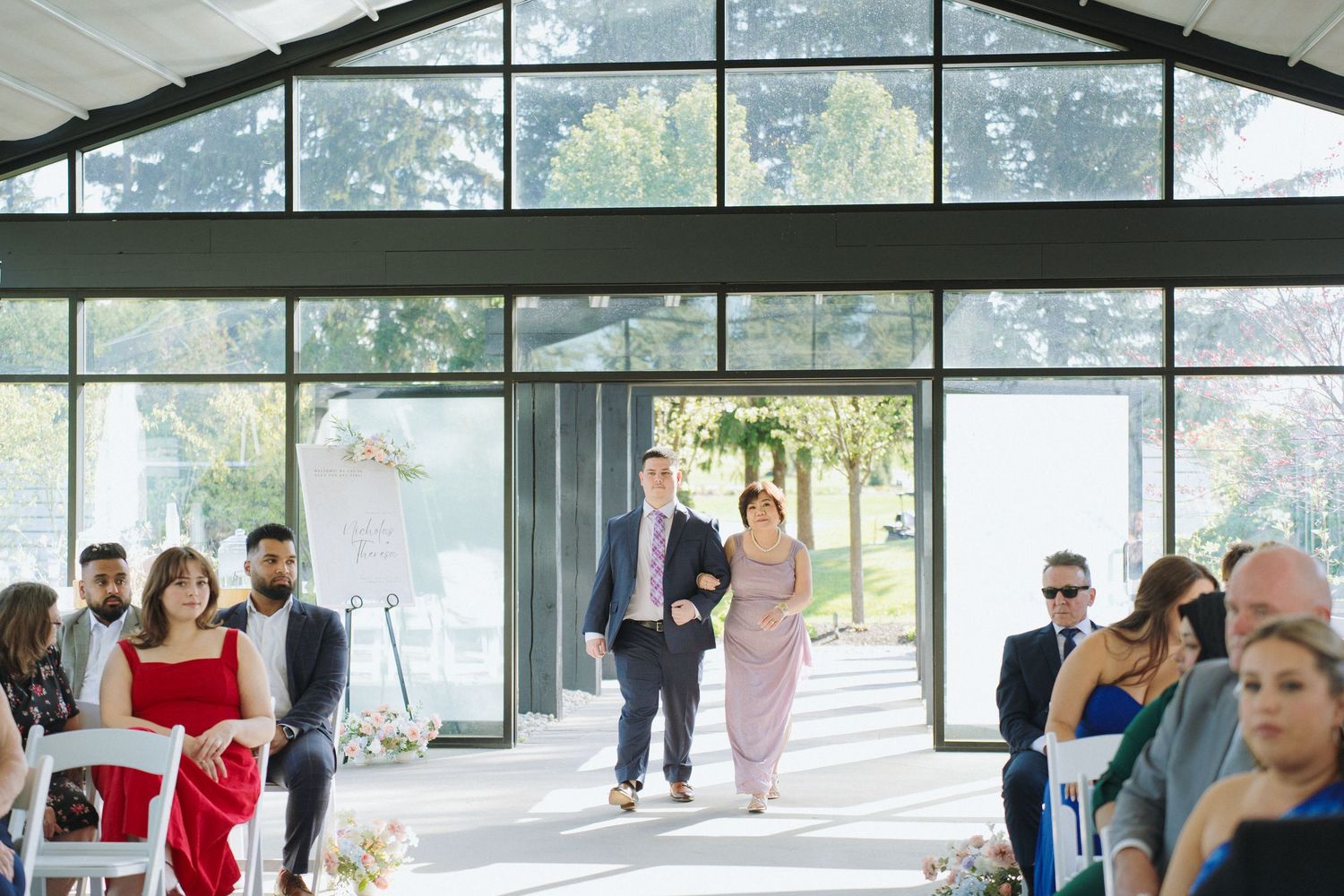 Wedding venue interior showing vaulted ceiling, chandeliers and wall of windows.