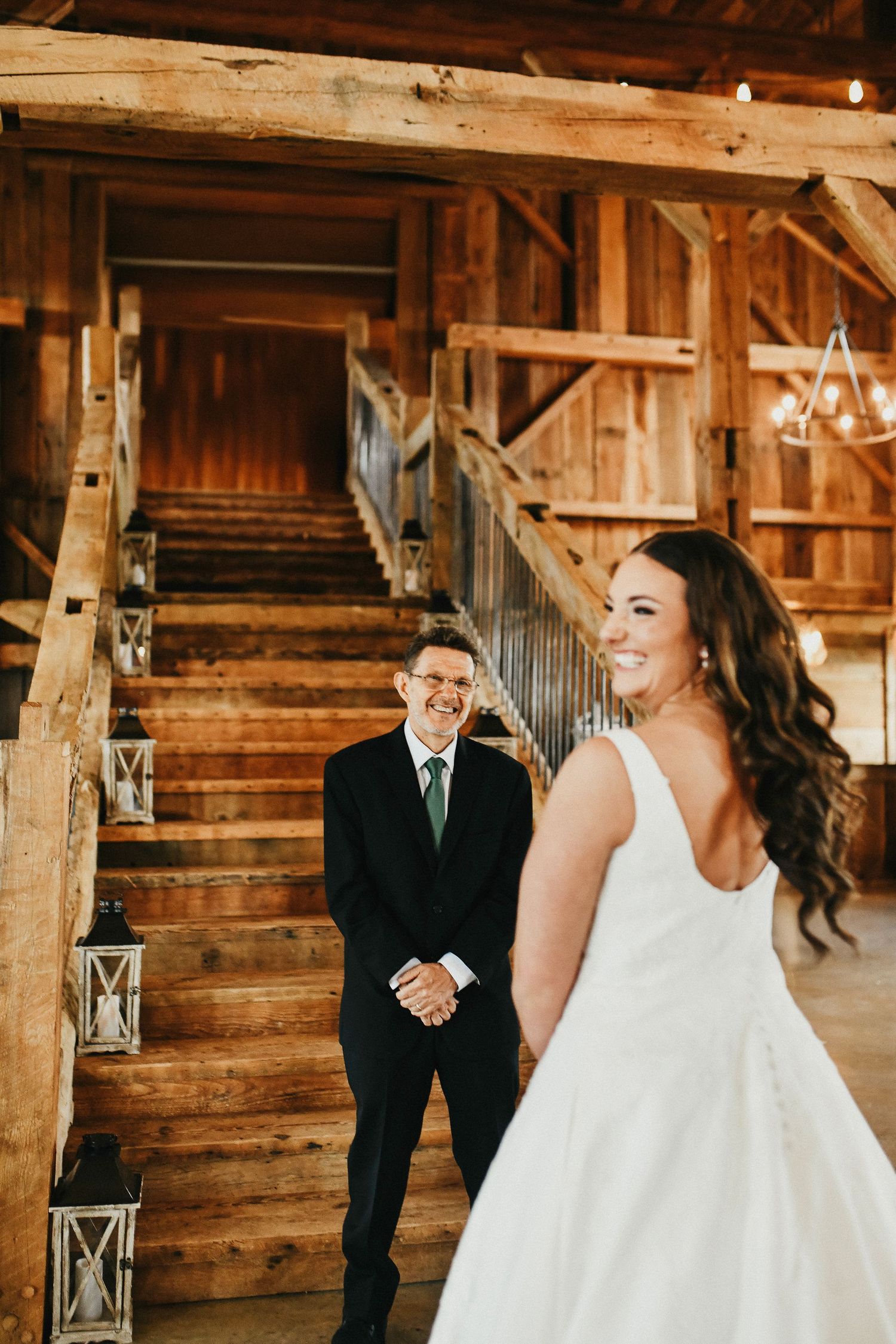 the bride laughs as her father sees her for the first time as they have their first look on the rustic staircase of the madelyn