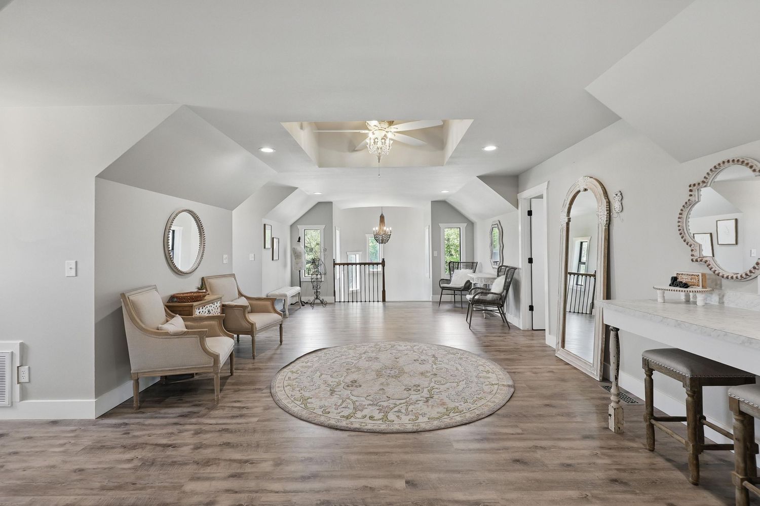 Modern living room interior with arched doorways, circular gray rug, wood floors and elegant neutral decor.