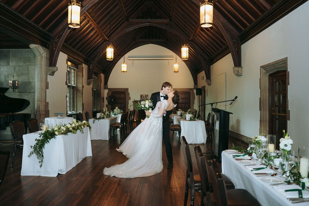 Decorative floral arrangements adorn wooden beams and lanterns in an elegant wedding venue.